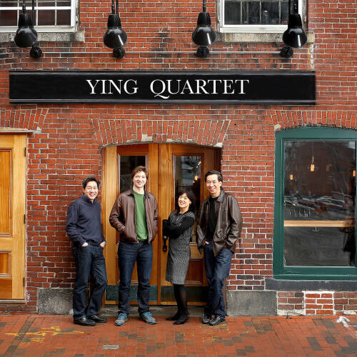 The Ying Quartet standing in front of a brick building, sign above reads Ying Quartet